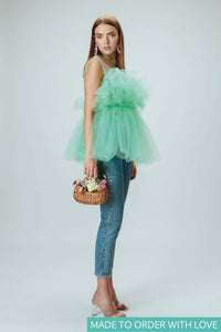 Model is wearing mint green tulle top holding a flower basket